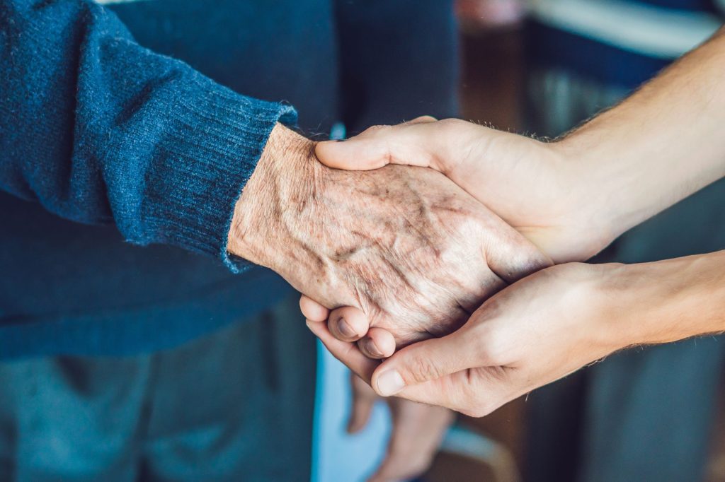 Badante stringe mano anziano