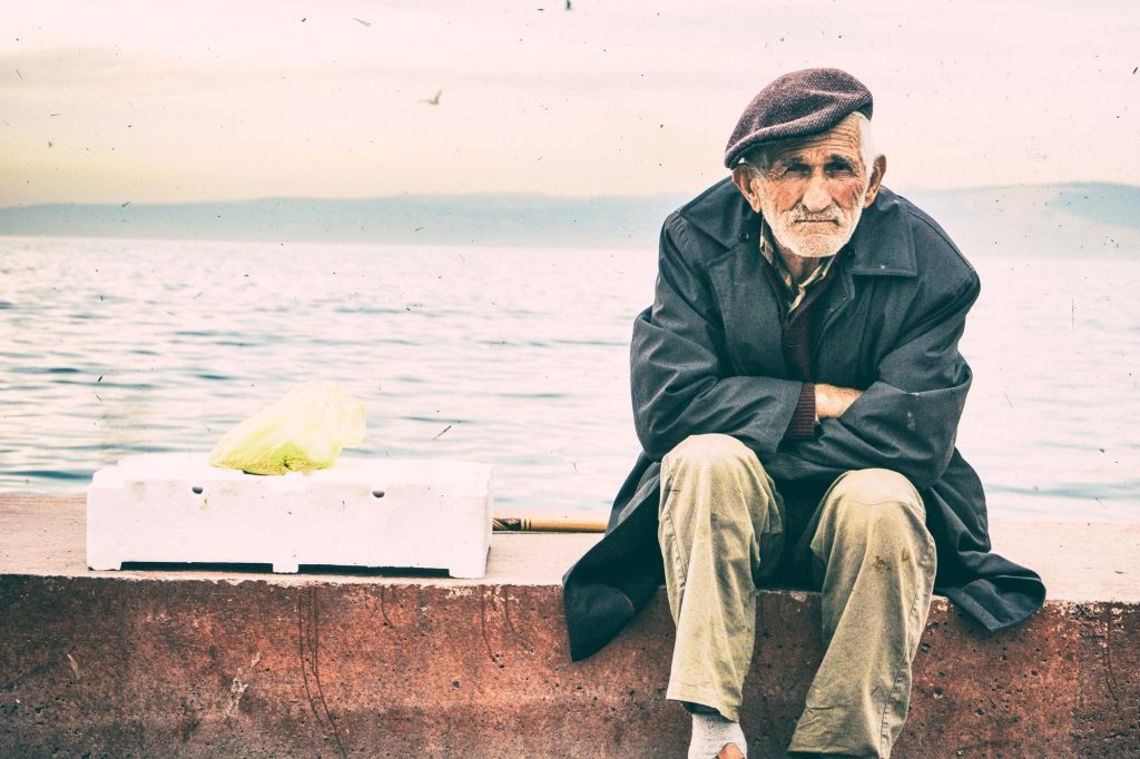 Anziano seduto vicino al mare