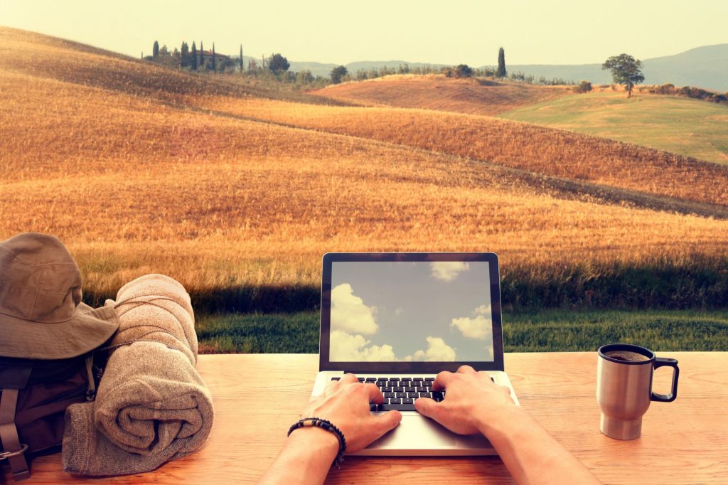 Nomade digitale che utilizza un computer portatile da una città italiana collinare