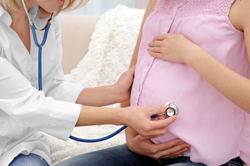Dottoressa ausculta pancia di donna incinta