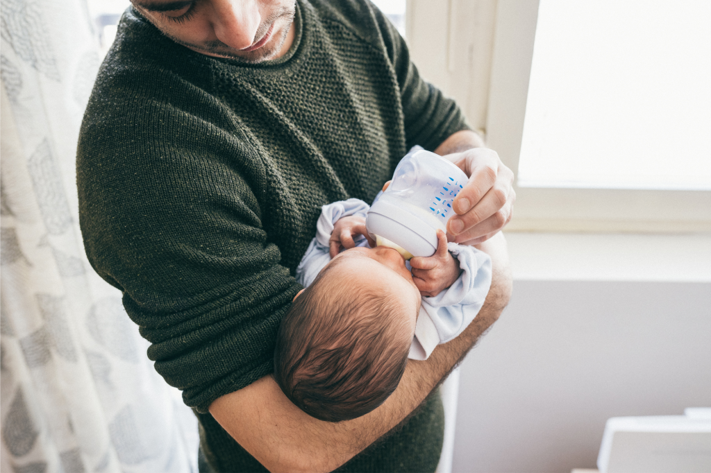 Un papà dà il latte con il biberon al figlio neonato