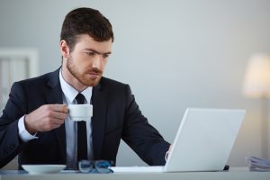 Bonus giovani under 35, giovane al lavoro al pc con tazza di caffè