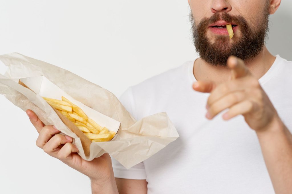 Uomo che mangia patatine fritte