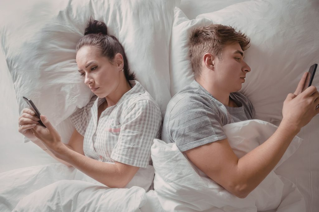 Coppia a letto con lo smartphone - Canva